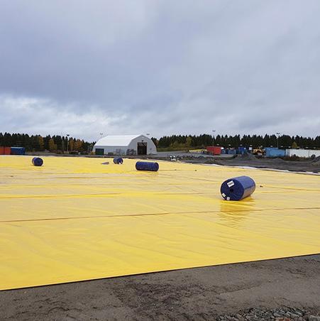 A large roof covered in yellow membrane, with rolls ready to lay