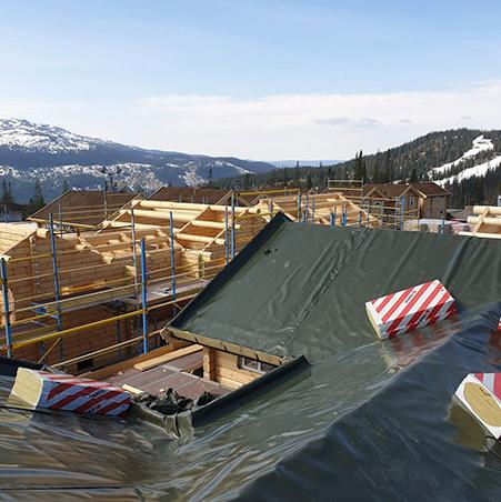 A roof under construction in the mountains, covered in dark underlay