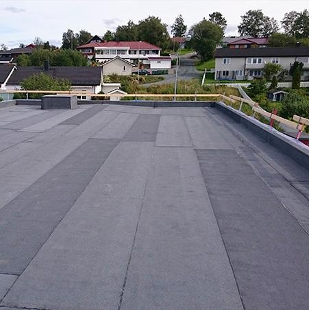 A new flat roof in dark membrane, with houses and gardens below